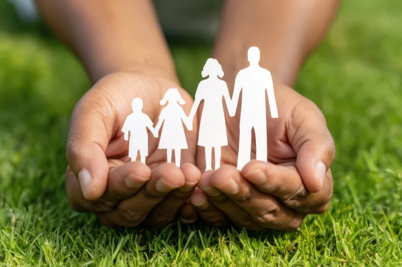Hands holding paper cutout family figures on grass