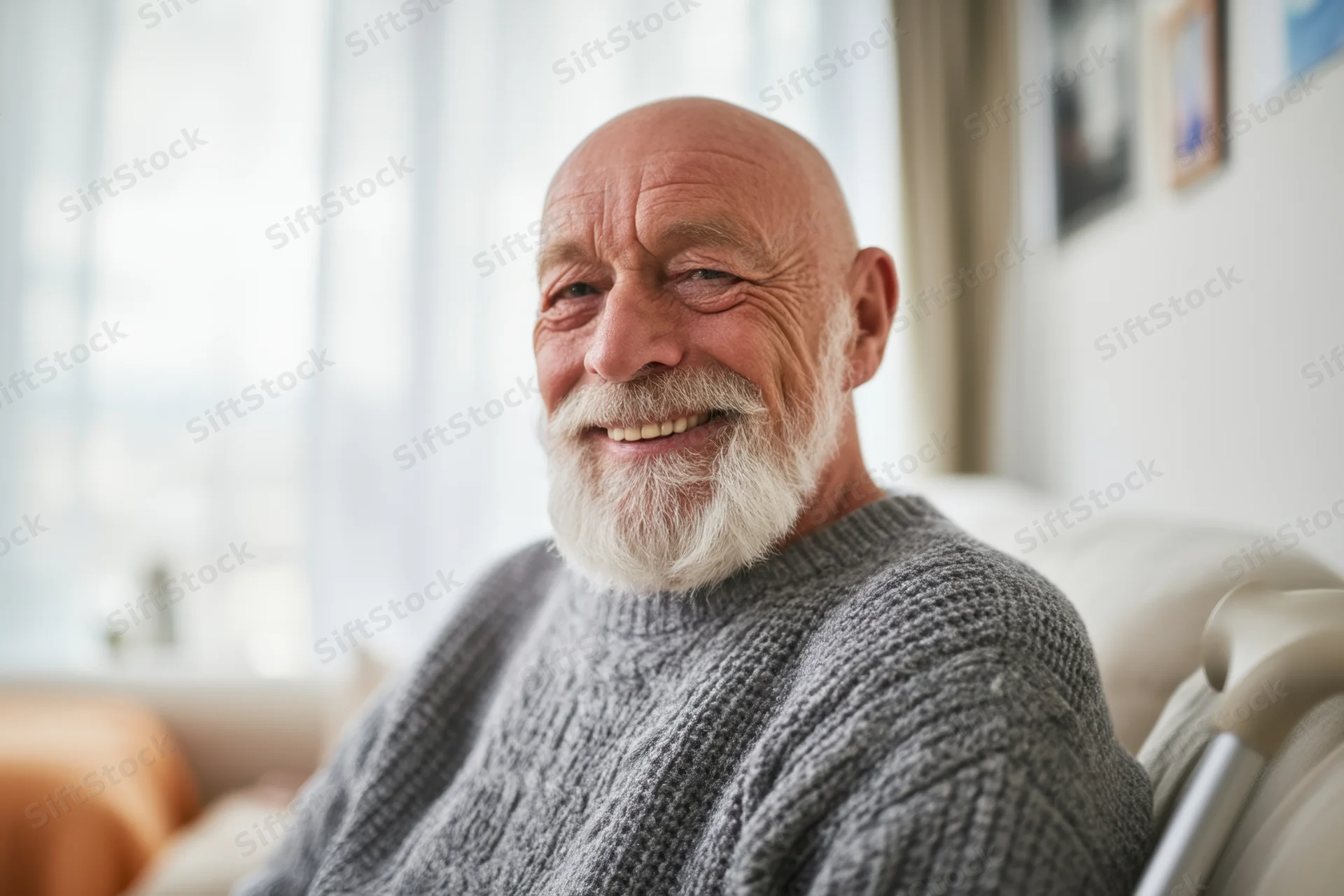 Senior man smiling while seated on a couch in a bright living room