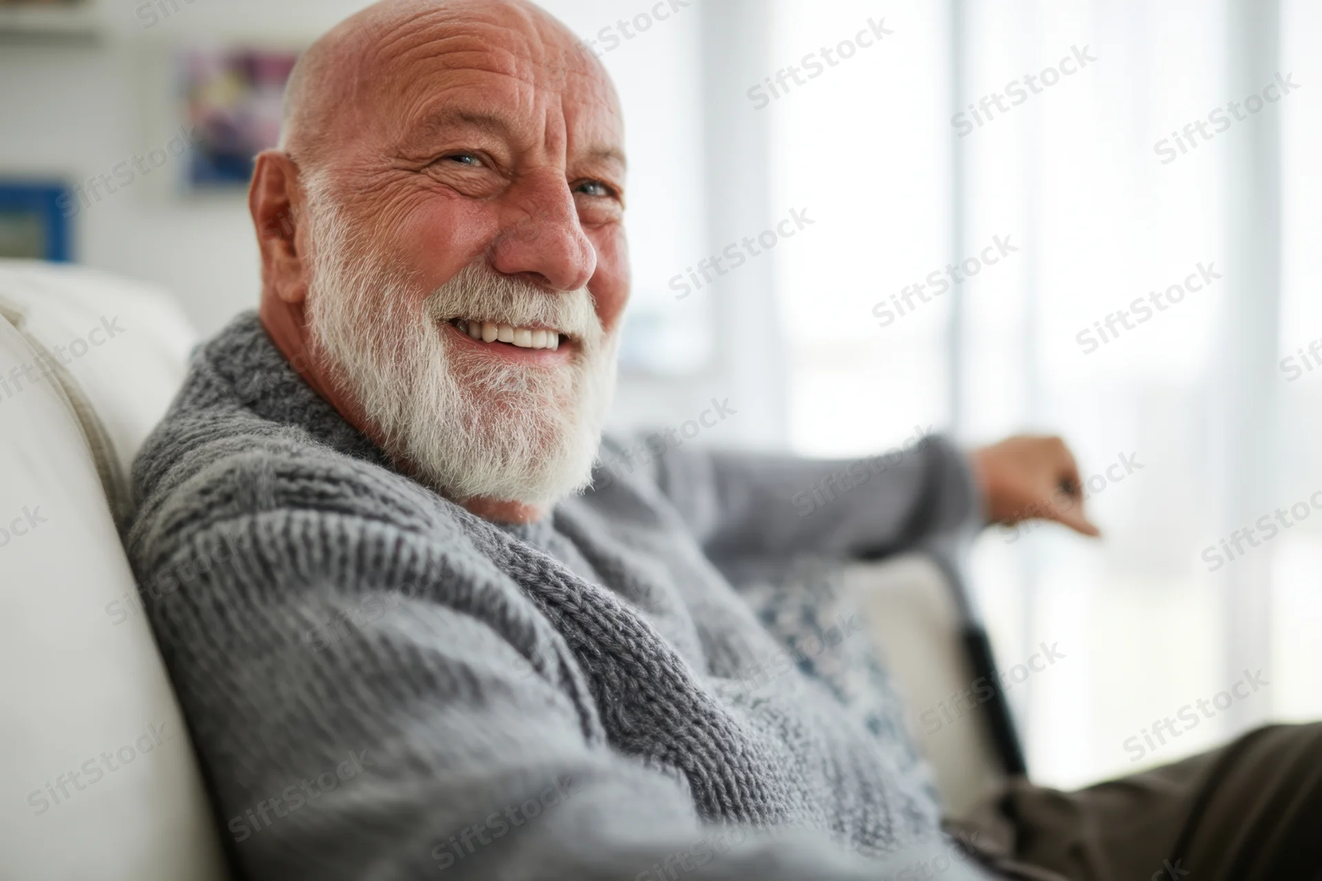 Elderly man smiling while relaxing on a couch in a bright living room