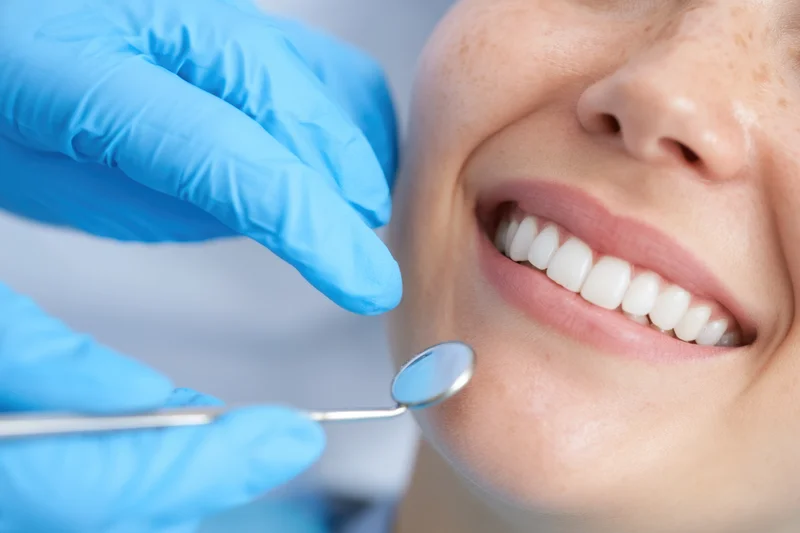 Dentist examining patient's teeth with dental mirror in clinic