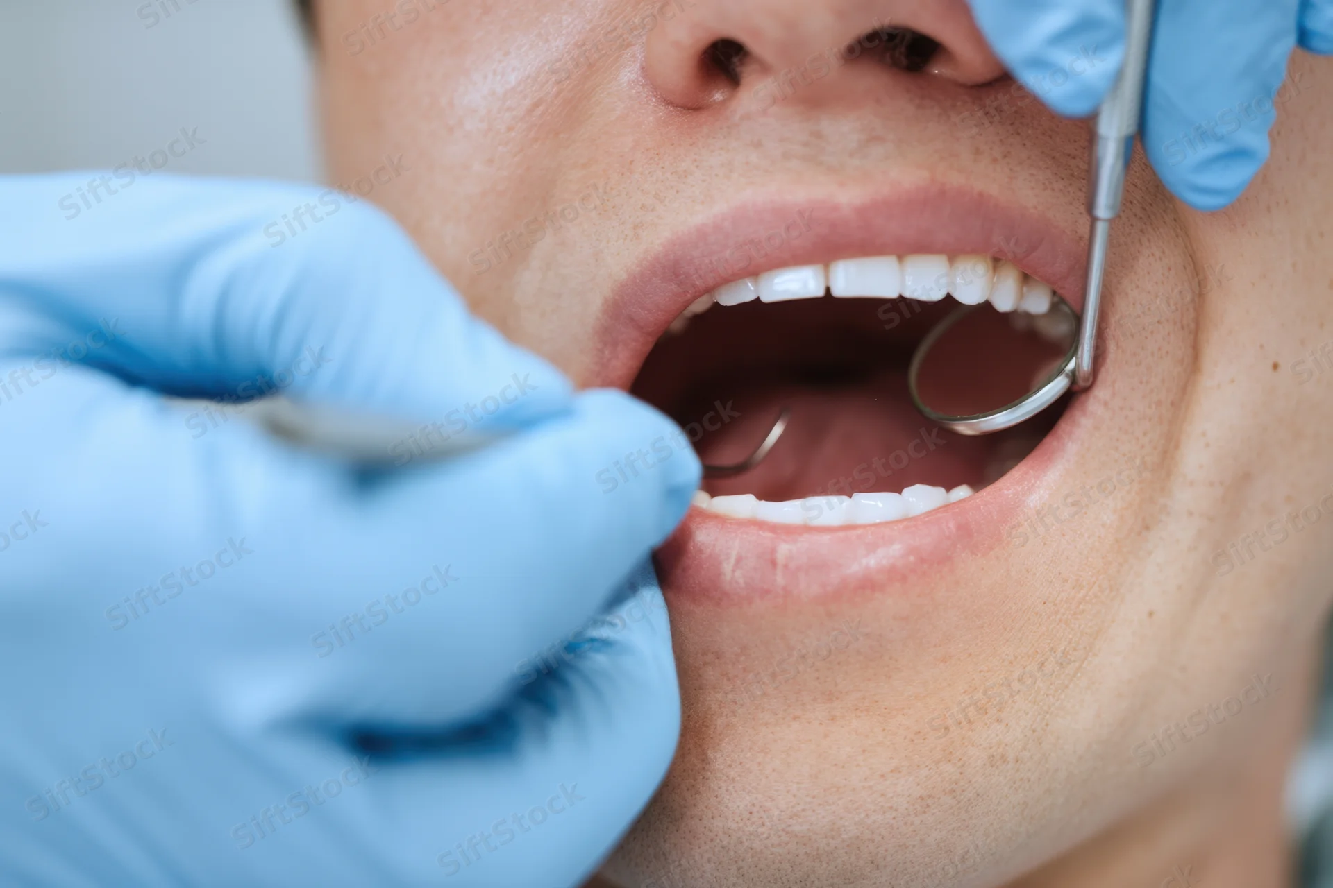 Dentist examining teeth with mirror and probe in clinic