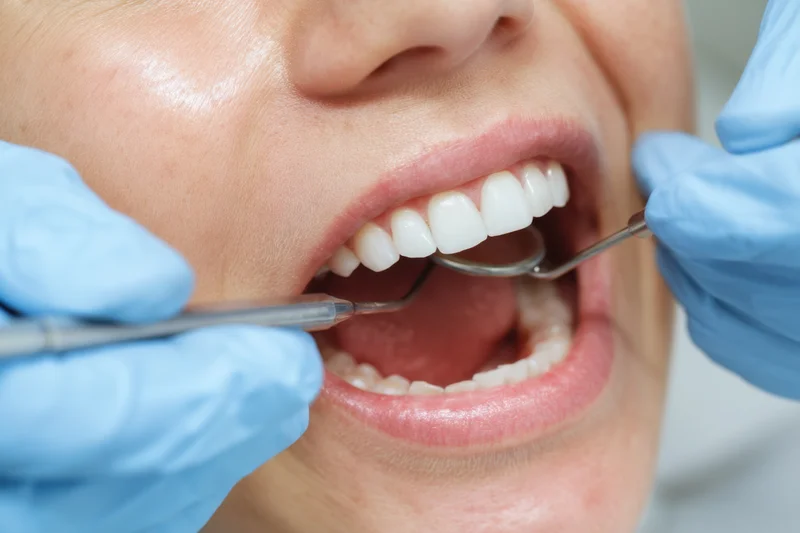 Dentist examining teeth with mirror and probe in a patient's open mouth