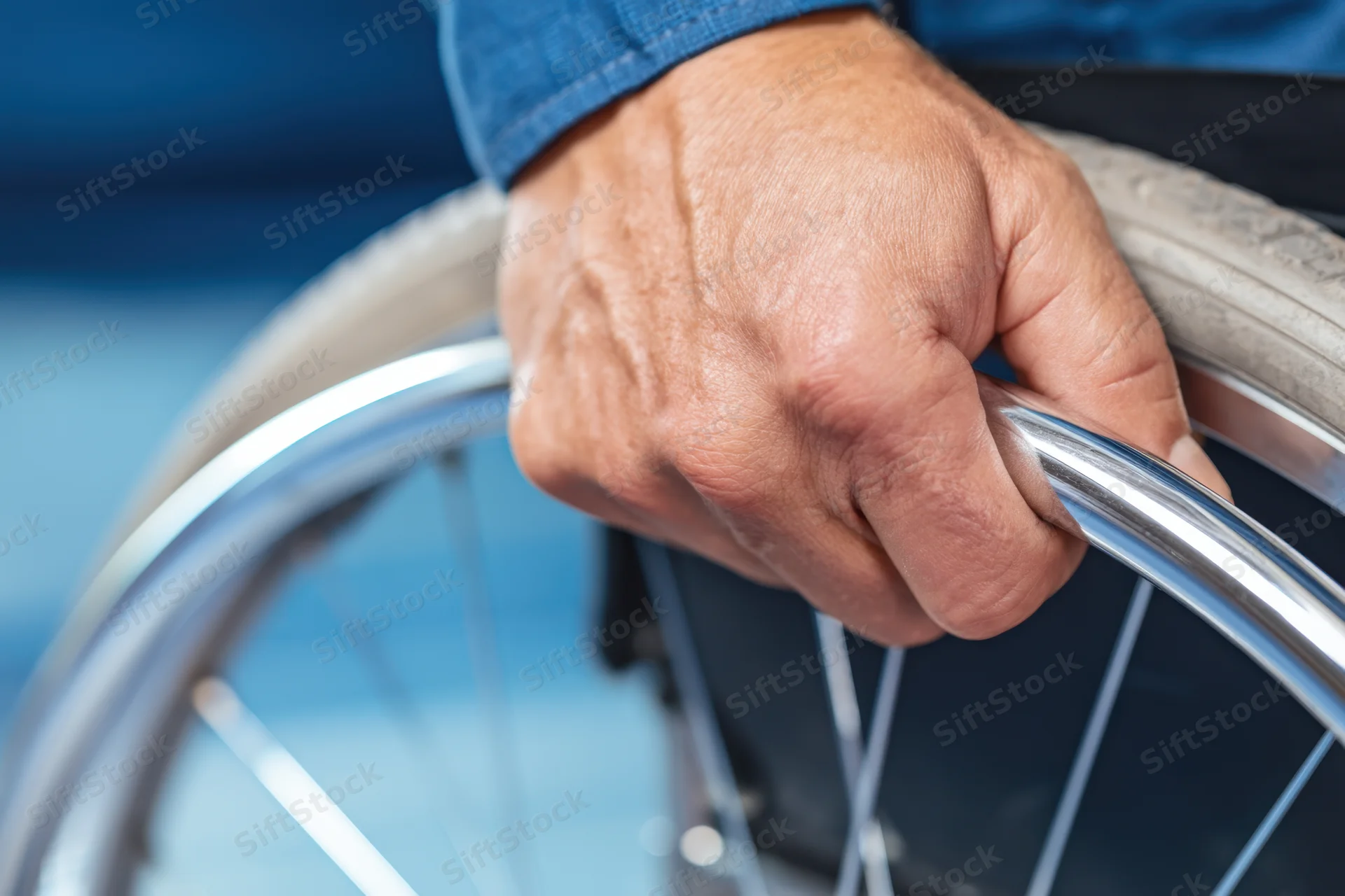 Close-up of a man's hand gripping the wheel of a wheelchair