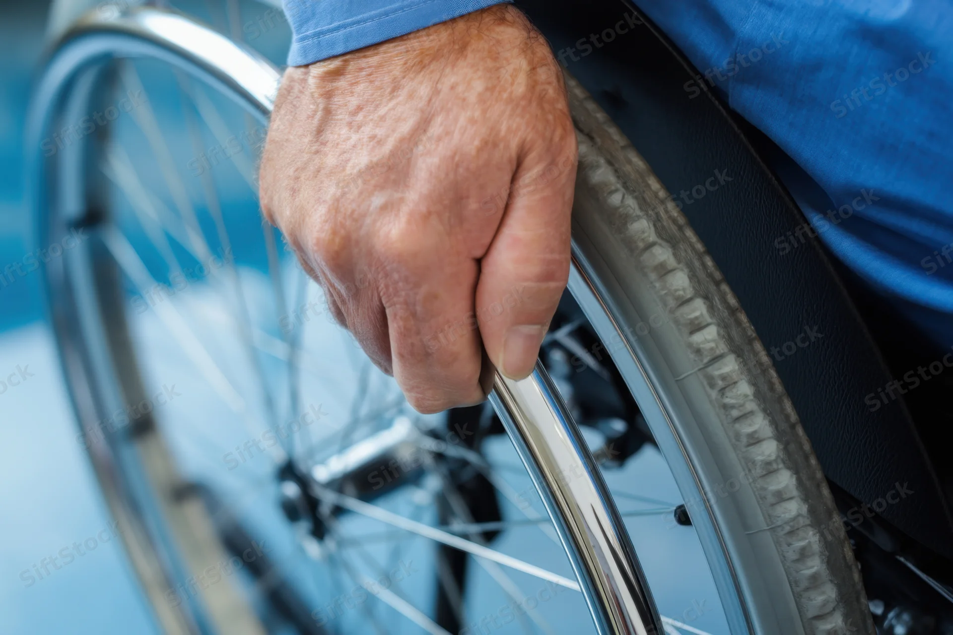 Close-up of a man's hand gripping the rim of a wheelchair wheel