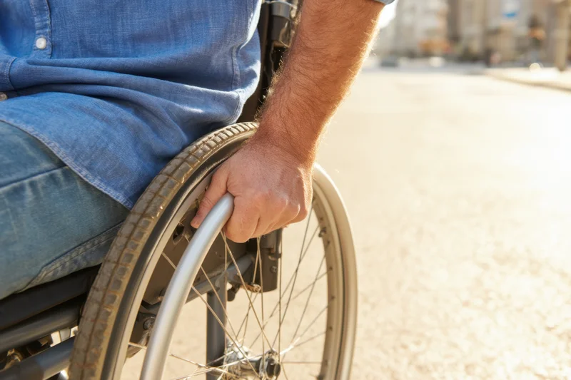 Man in wheelchair propelling himself on a city street