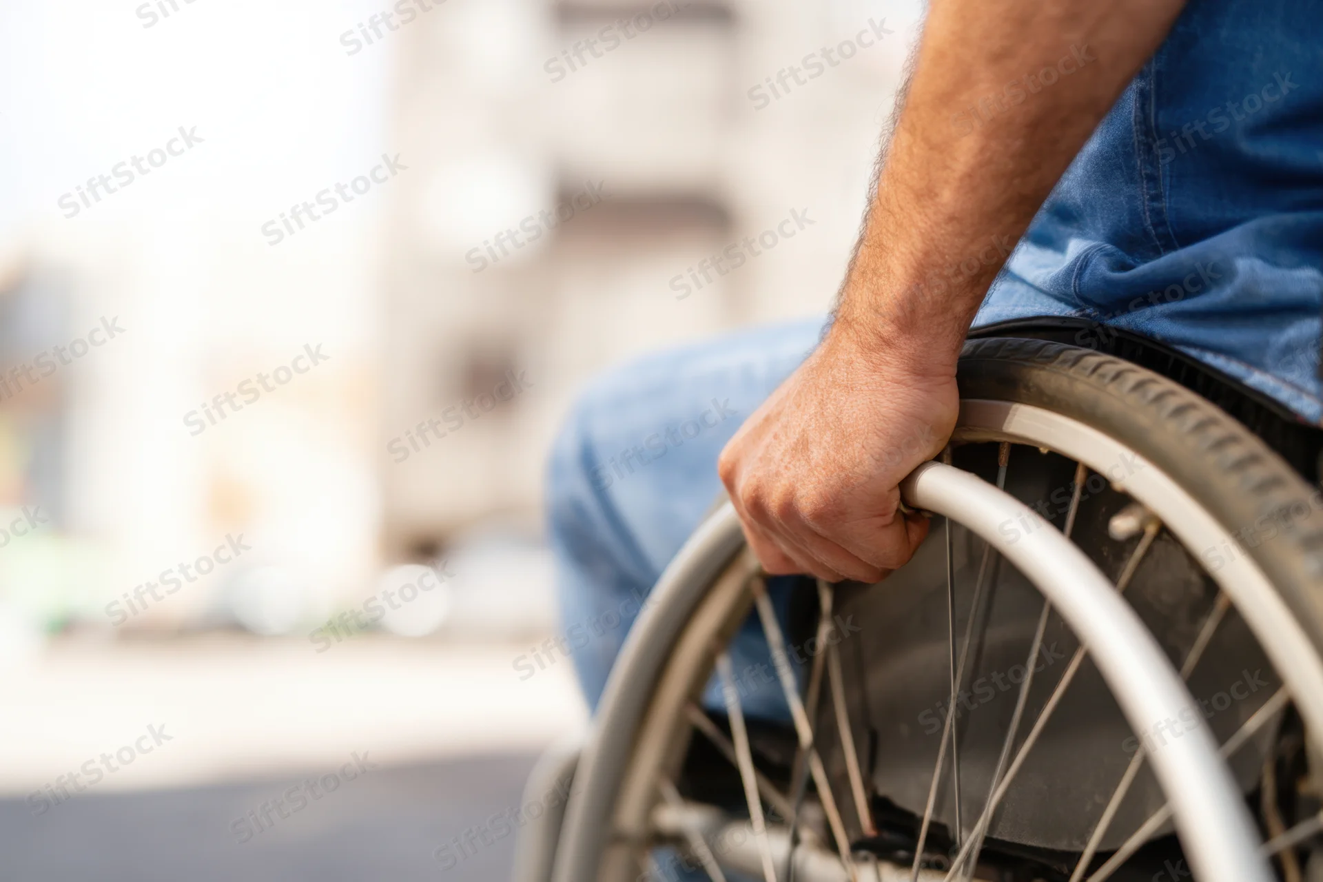 Man gripping wheelchair wheel outdoors on a street