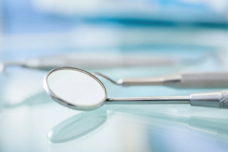 Dental mirror and instruments resting on a reflective surface in a clinical setting