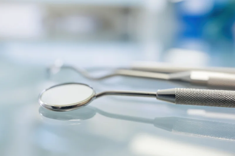 Dental mirror and explorer resting on a reflective surface in a clinic setting