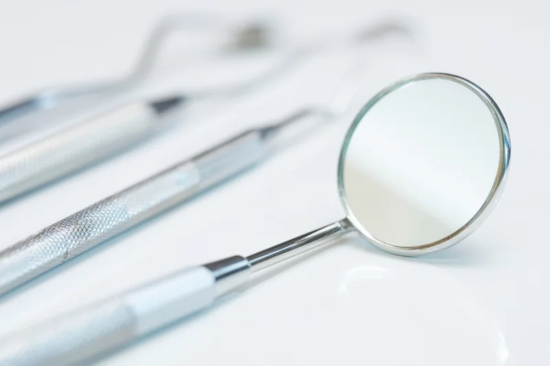 Dental mirror and instruments on white surface