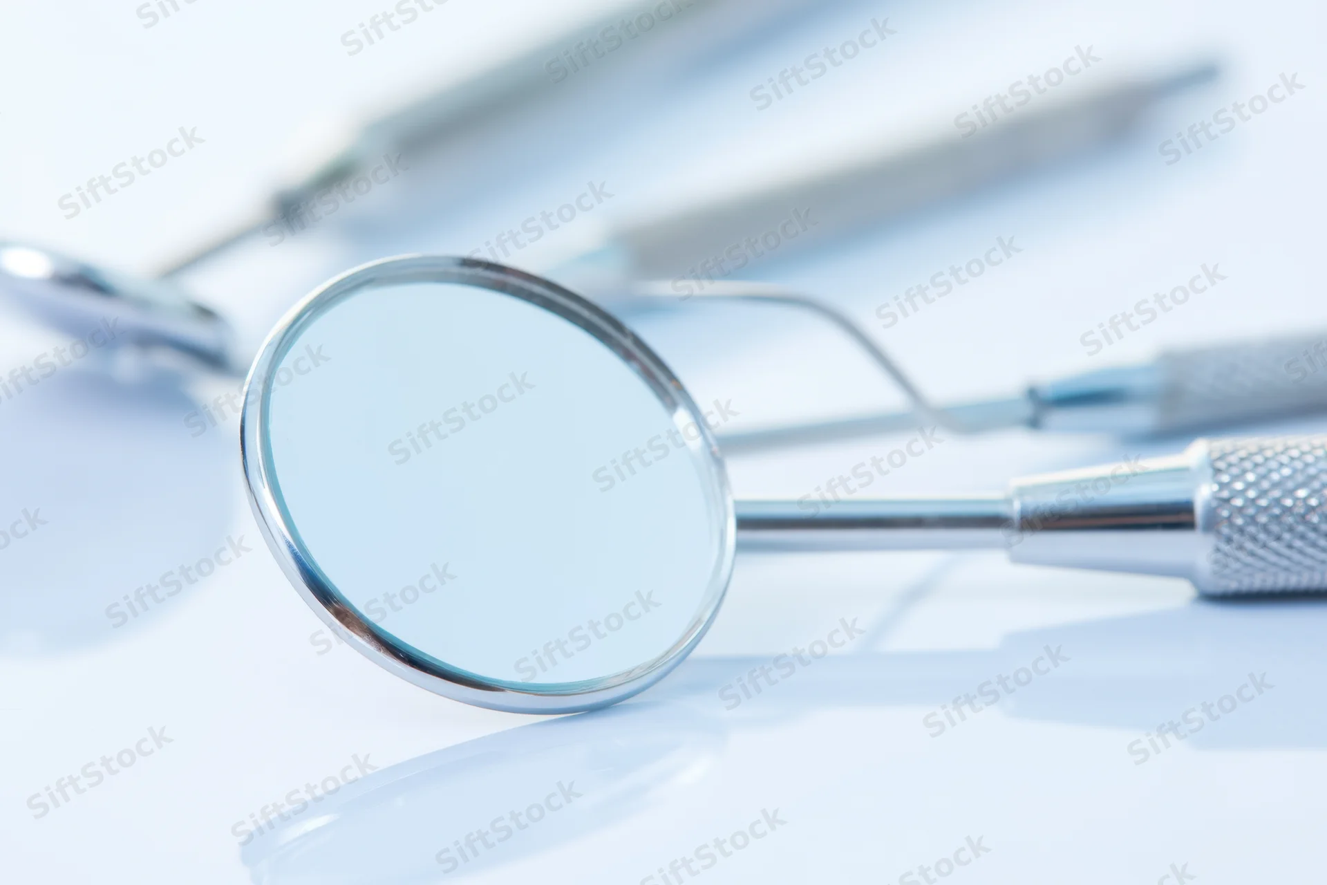 Dental mirror and instruments on a clean white surface