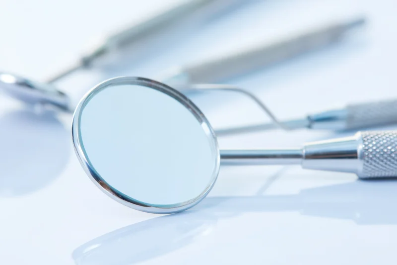Dental mirror and instruments on a clean white surface