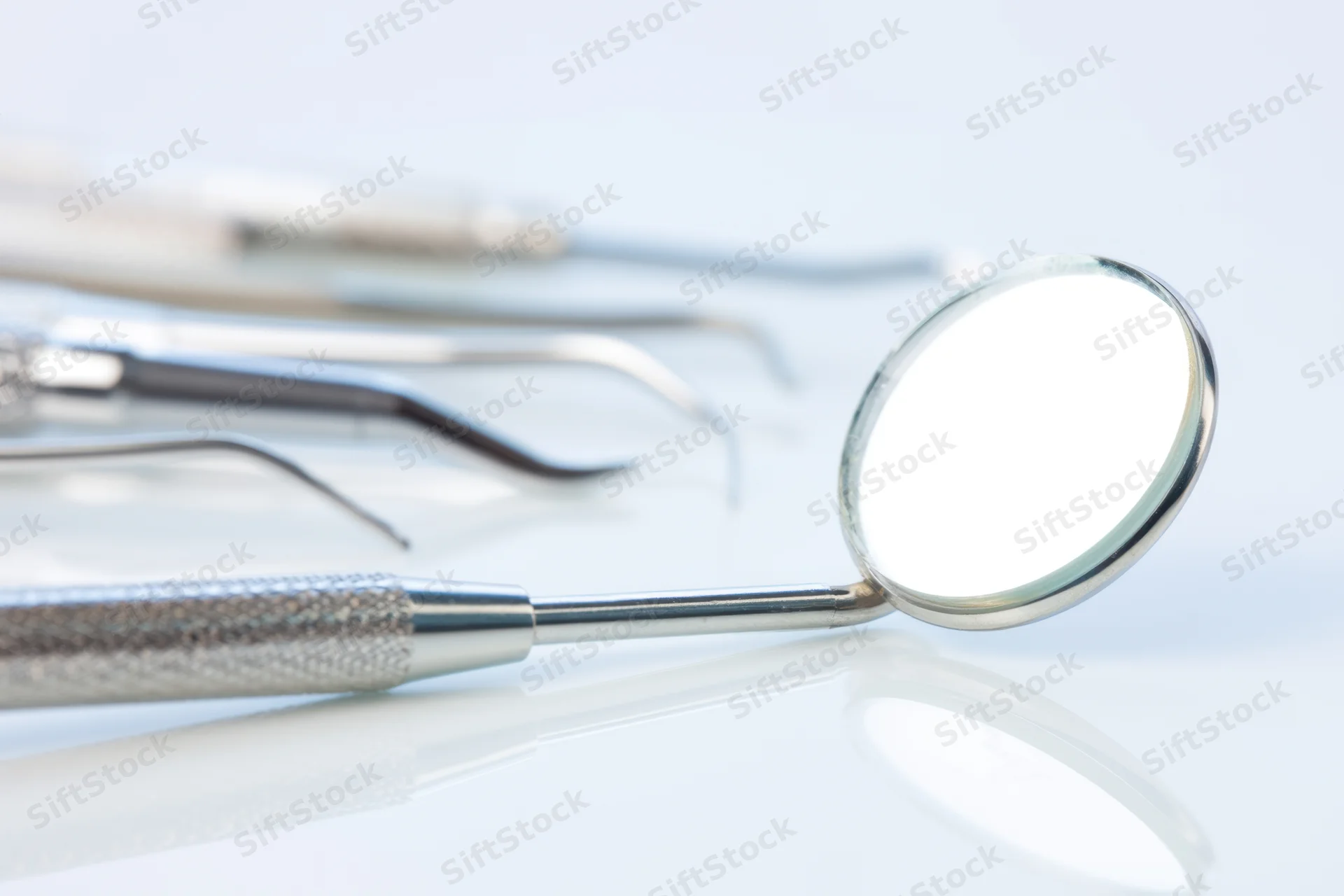 Dental mirror and instruments arranged on a reflective white surface