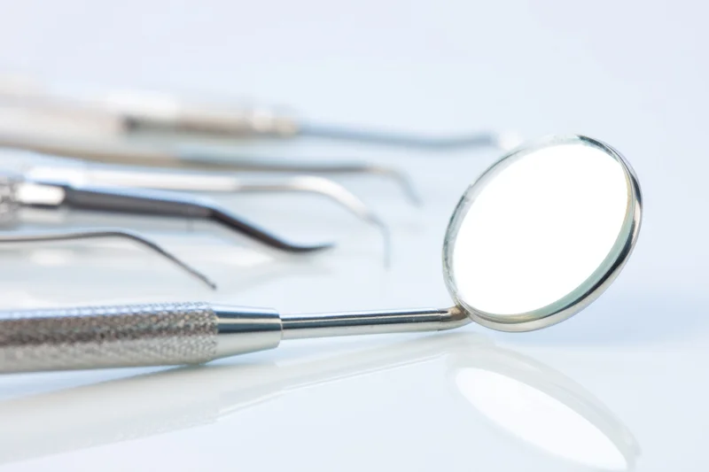Dental mirror and instruments arranged on a reflective white surface