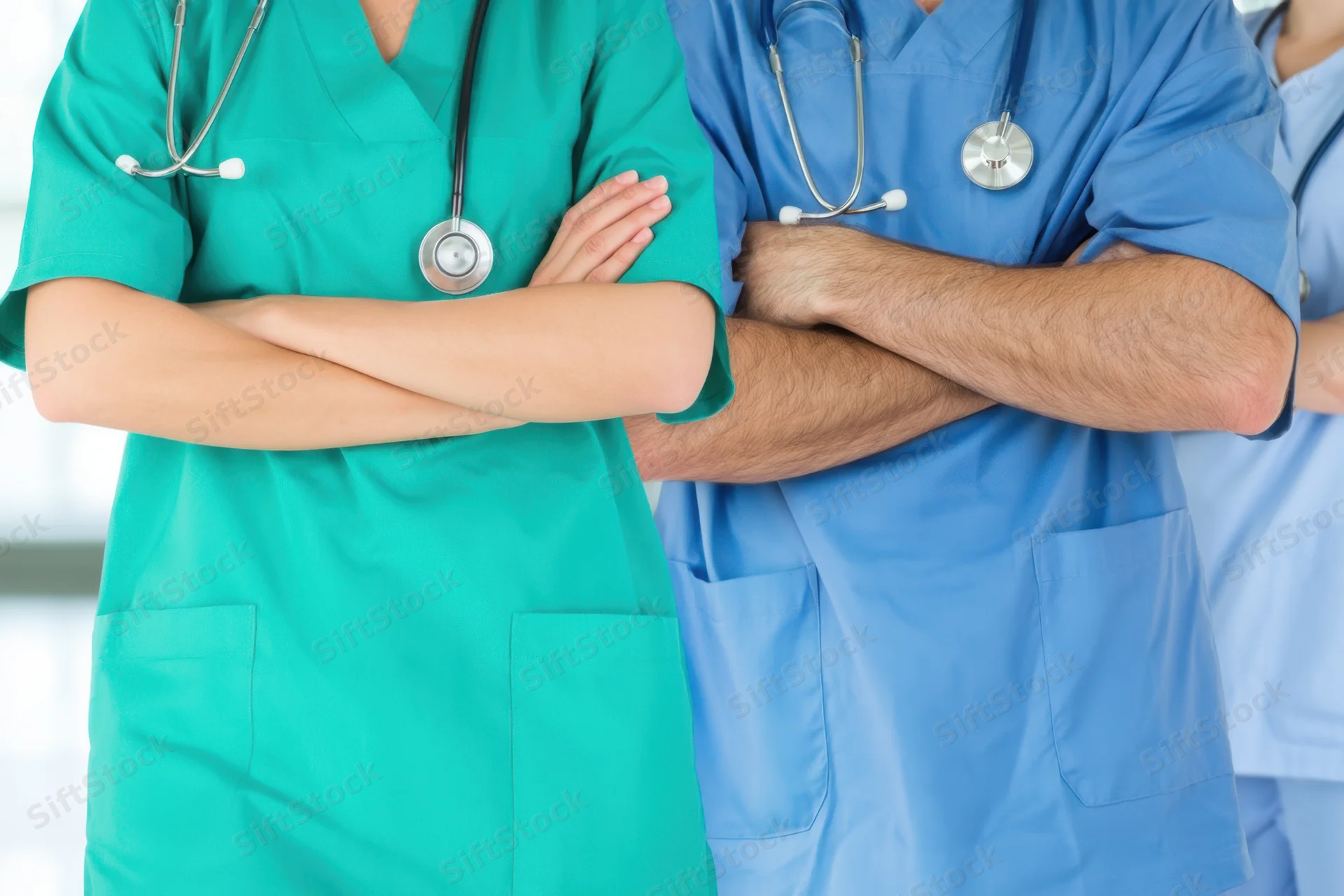 Medical professionals in scrubs with stethoscopes standing with arms crossed in a clinical setting