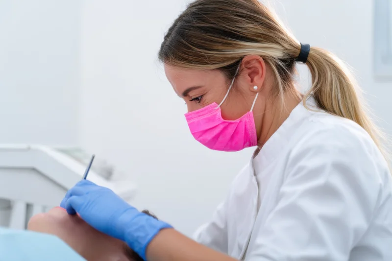 Female dentist performing dental procedure on patient in clinic