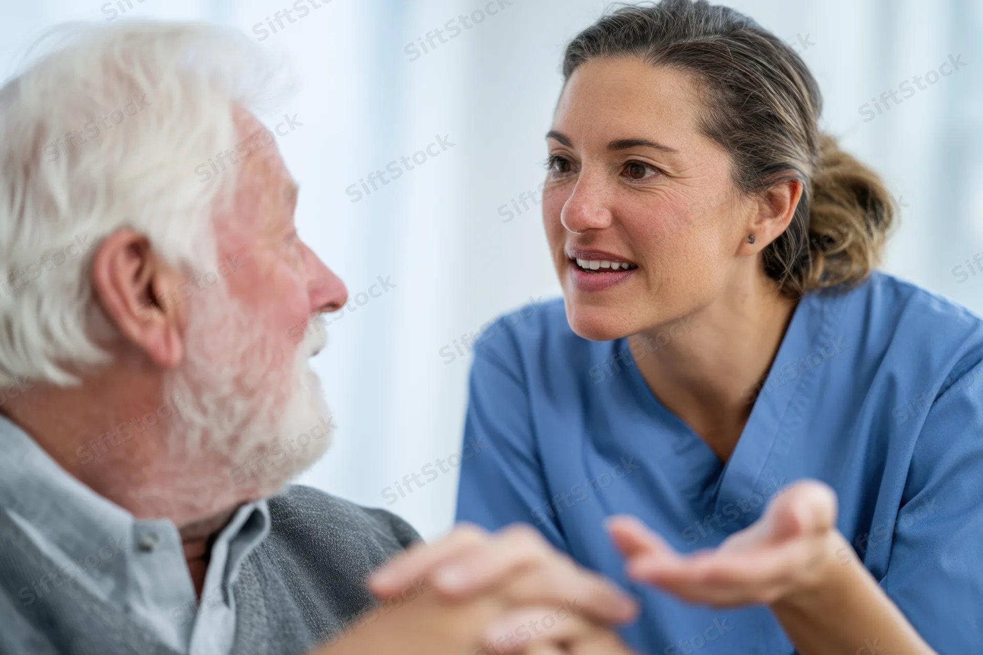 Nurse in blue scrubs talking with a senior man during a medical consultation