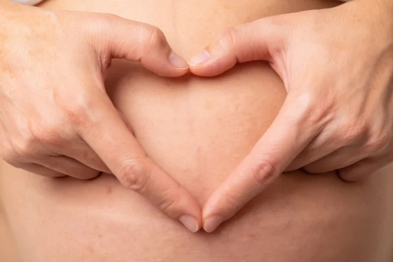 Woman's hands forming heart shape over pregnant belly