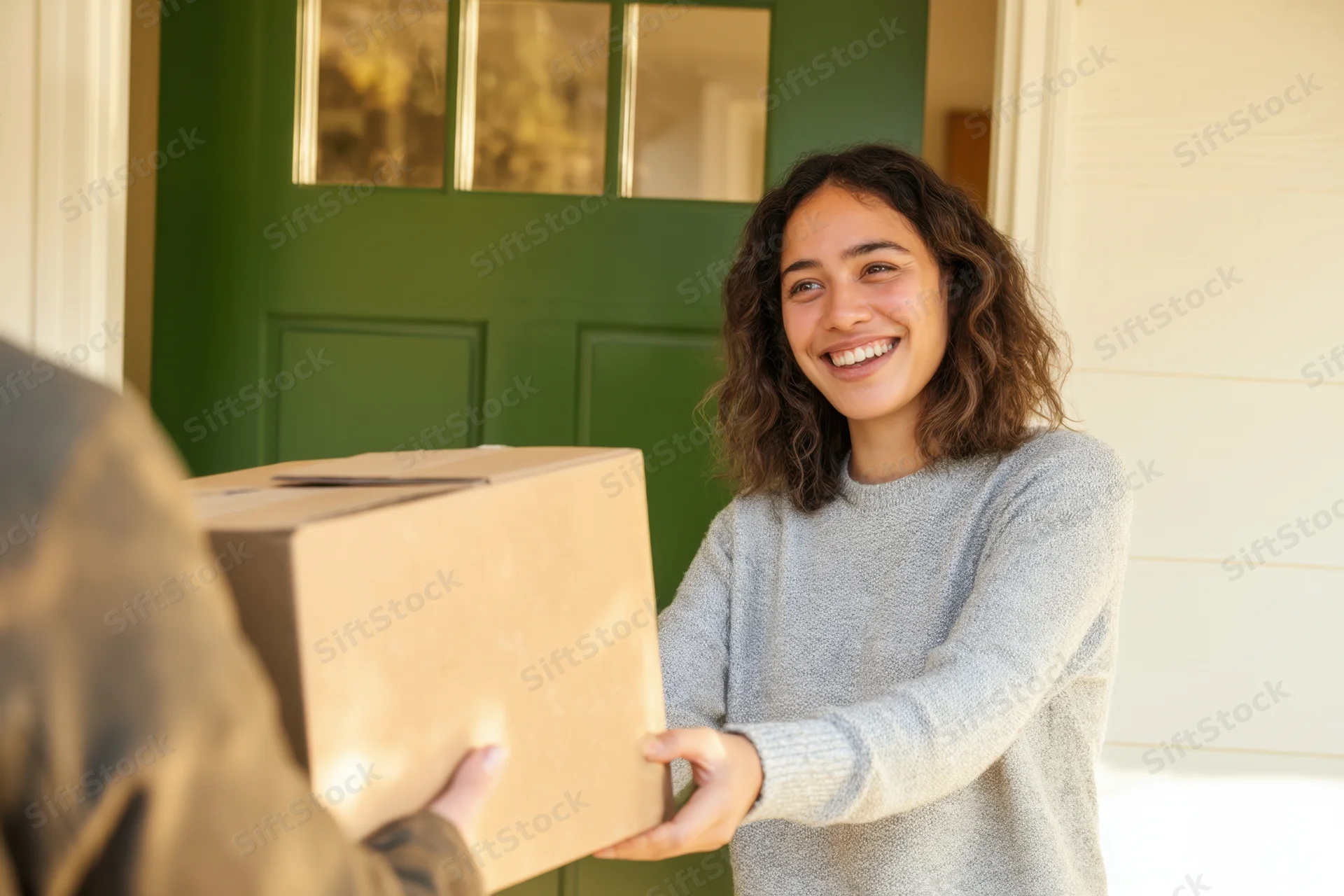 Woman receiving a package from a delivery person at her front door