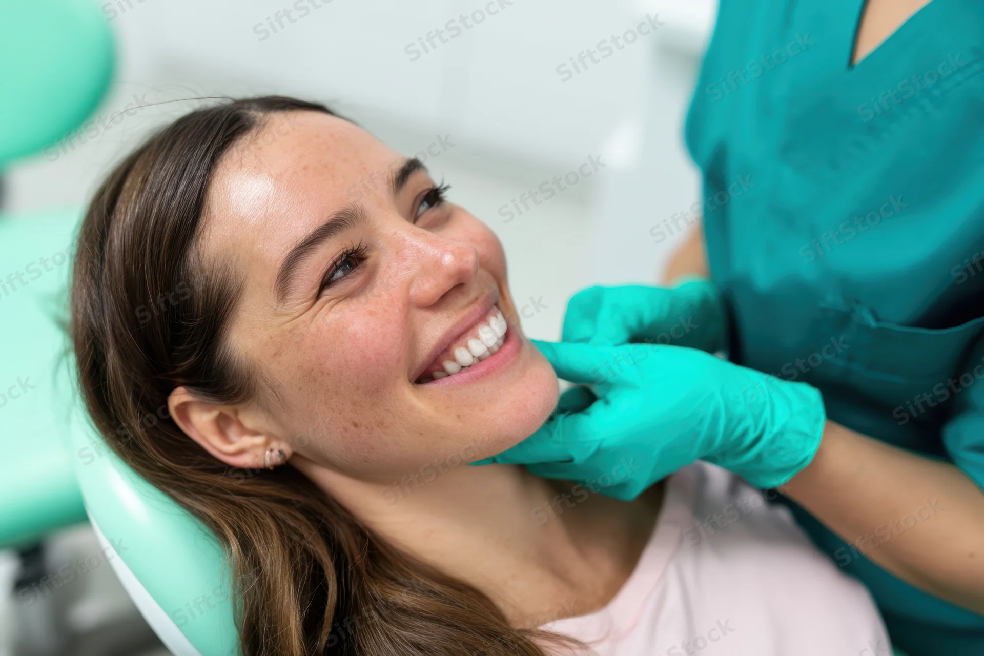 Smiling woman reclining in dental chair during examination by hygienist