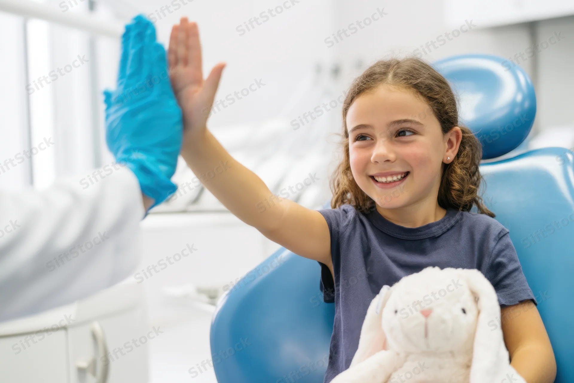 Young girl smiling and high-fiving dentist in dental clinic chair