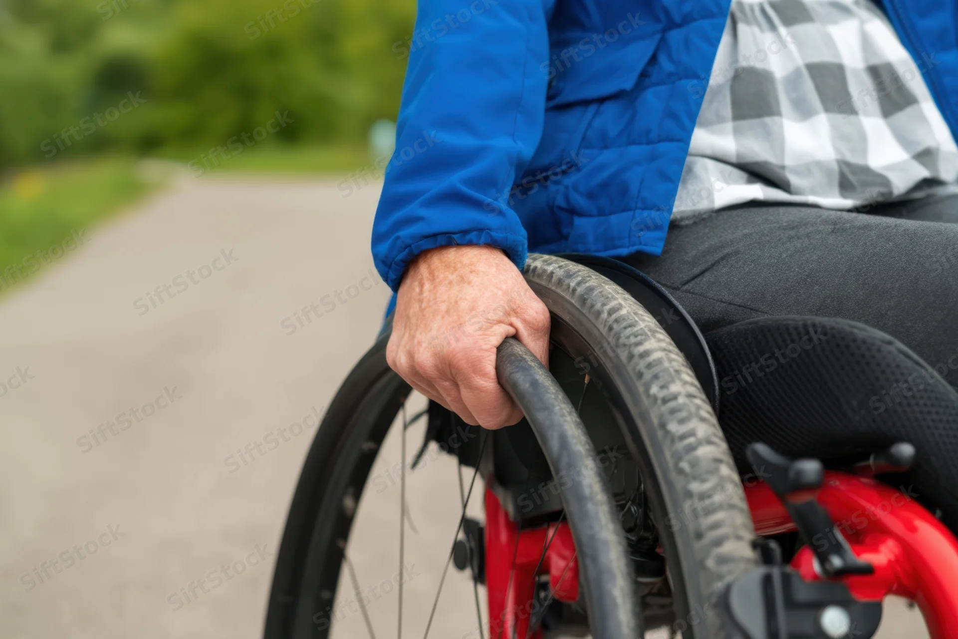 Person in wheelchair propelling themselves along a paved outdoor path