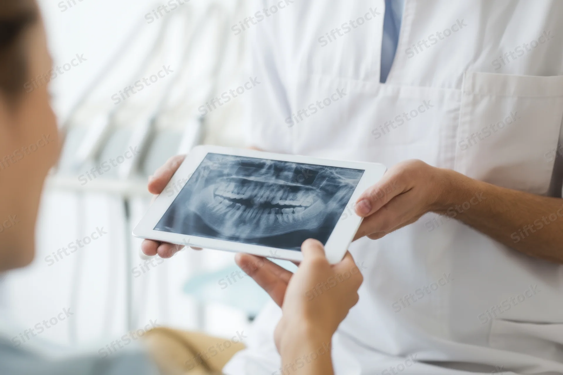 Dentist showing dental xray on tablet to patient during consultation in clinic
