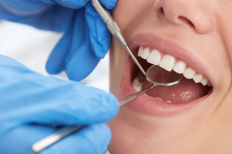 Dentist examining teeth with mirror and probe in patient's open mouth
