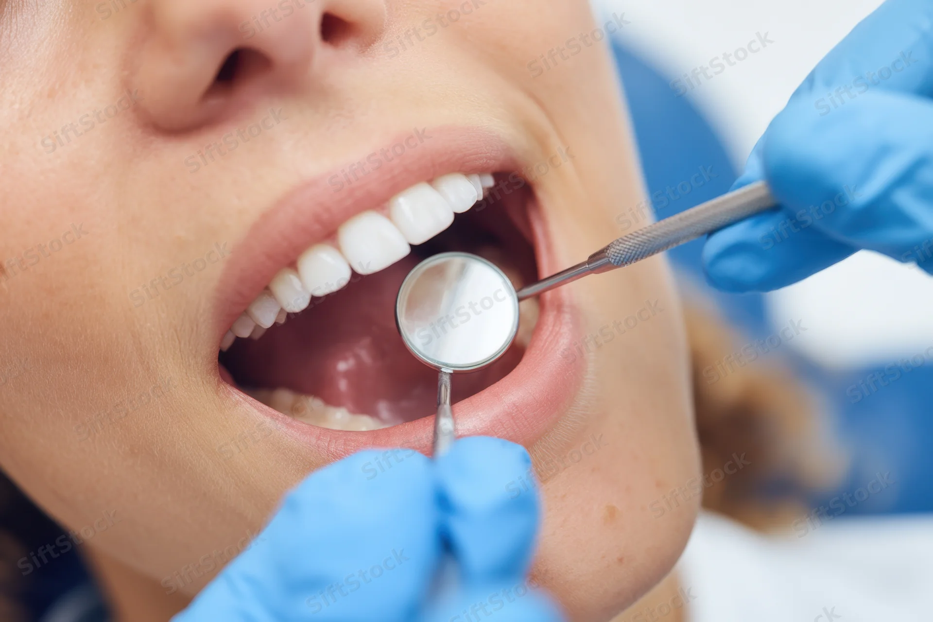 Woman undergoing dental examination with dentist using mirror and tool in clinic