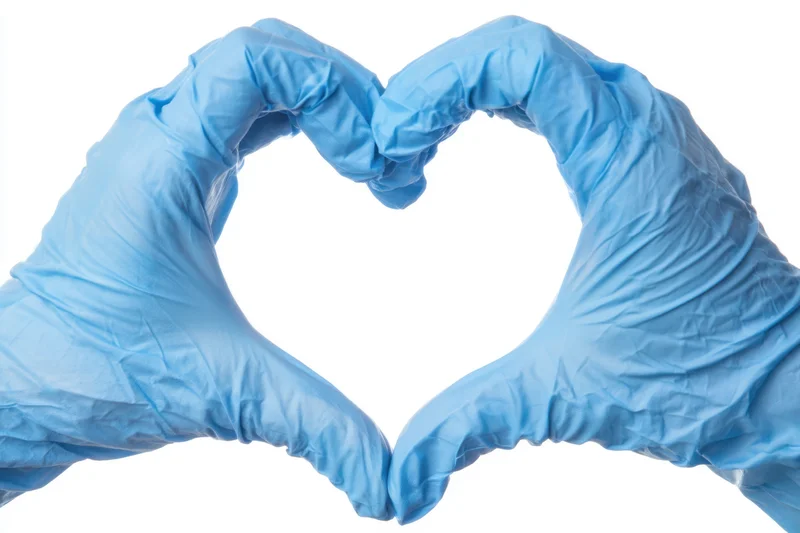 Hands in blue nitrile gloves forming a heart shape against white background