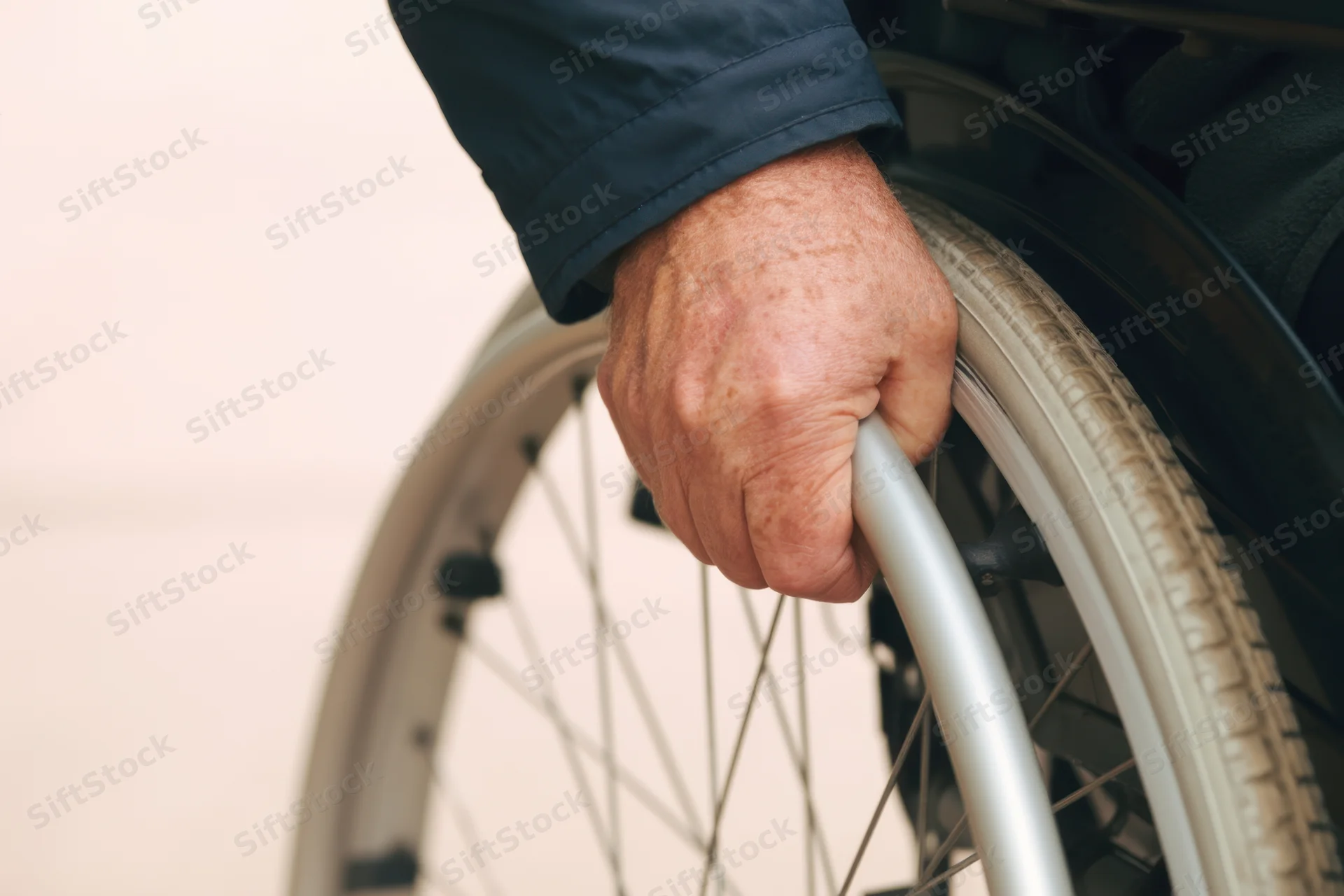 Close-up of a senior man's hand gripping the wheel of a wheelchair