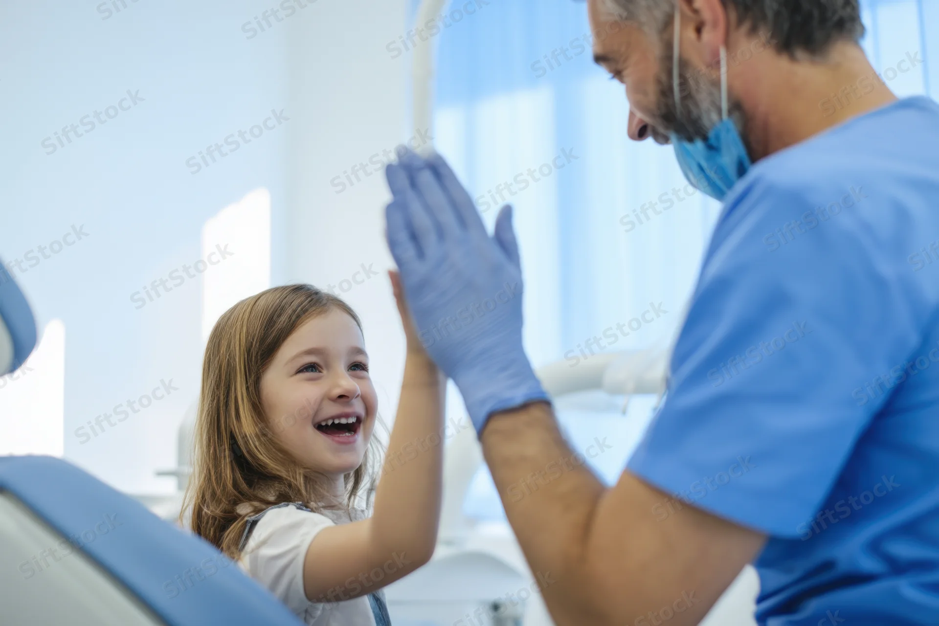 Young girl smiling and high-fiving a dentist in a dental clinic