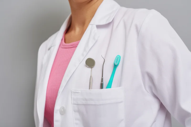 Woman in white labcoat with dental tools in pocket