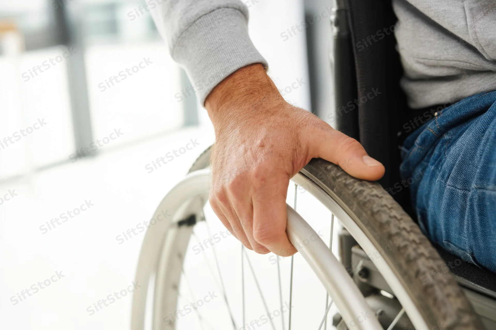 Man’s hand gripping wheelchair wheel indoors