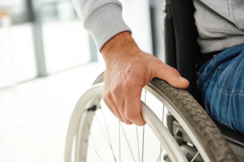 Man’s hand gripping wheelchair wheel indoors