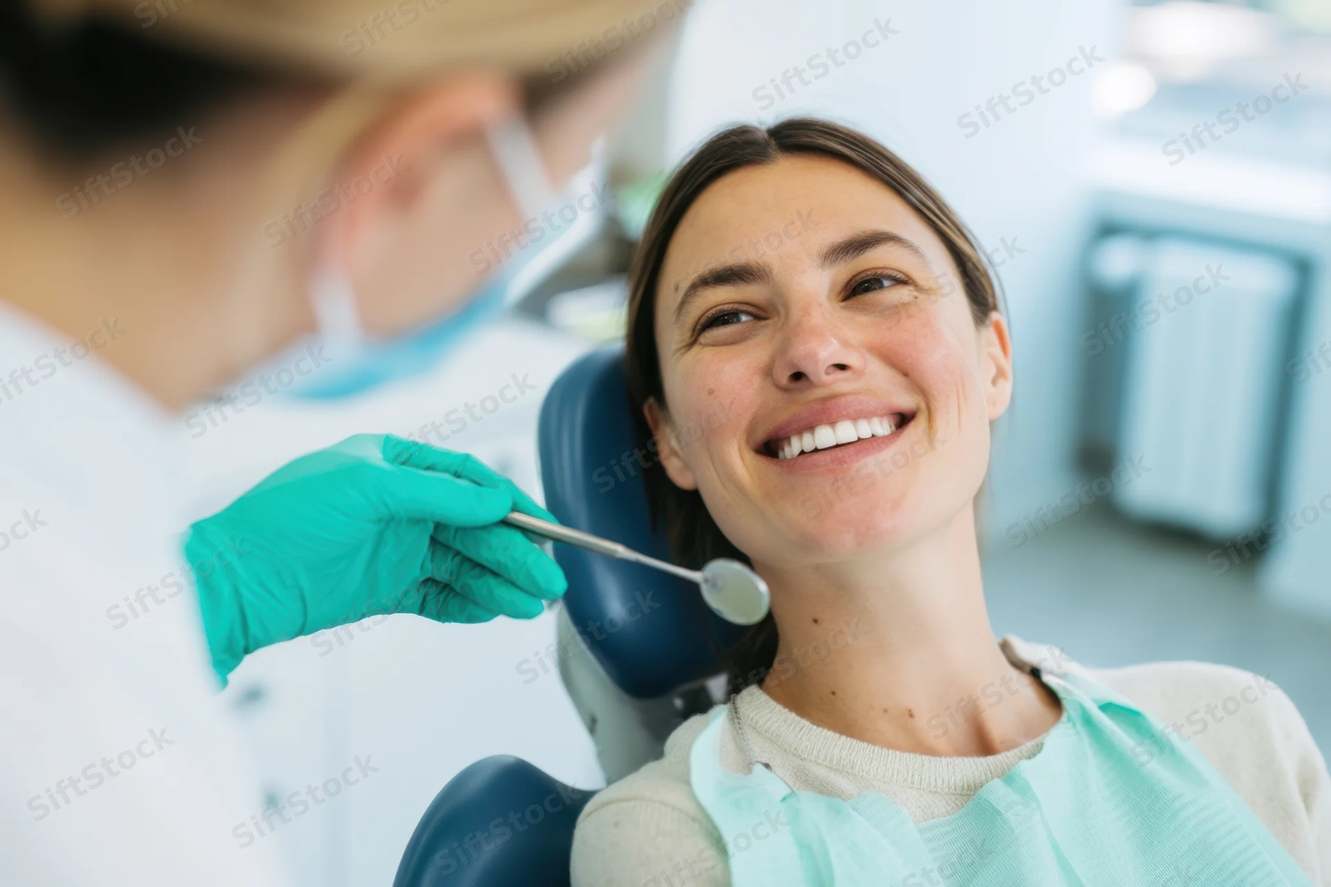 Smiling woman sitting in dental chair during examination by dentist