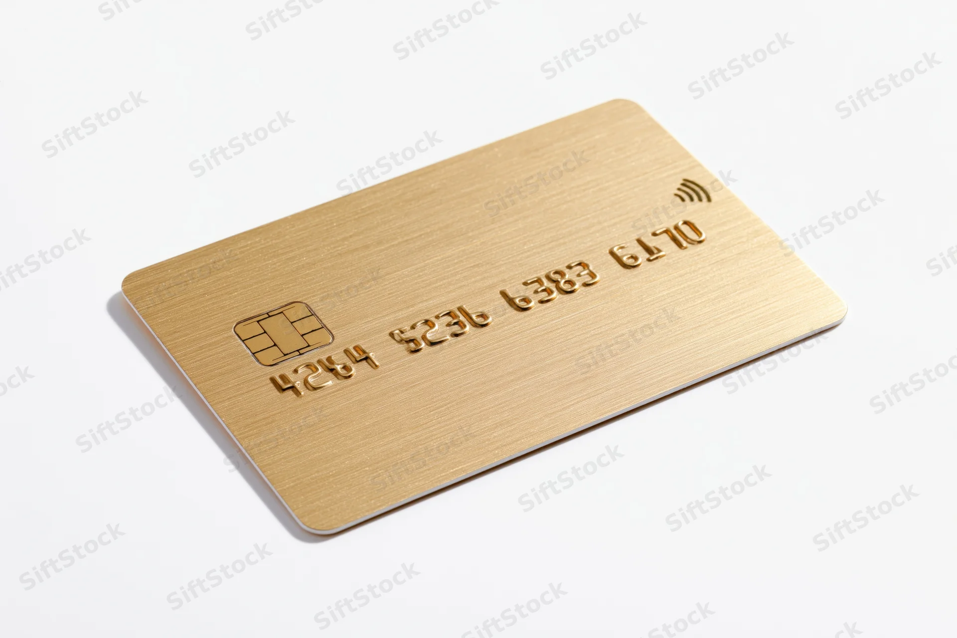Gold credit card with chip and contactless symbol lying flat on white background
