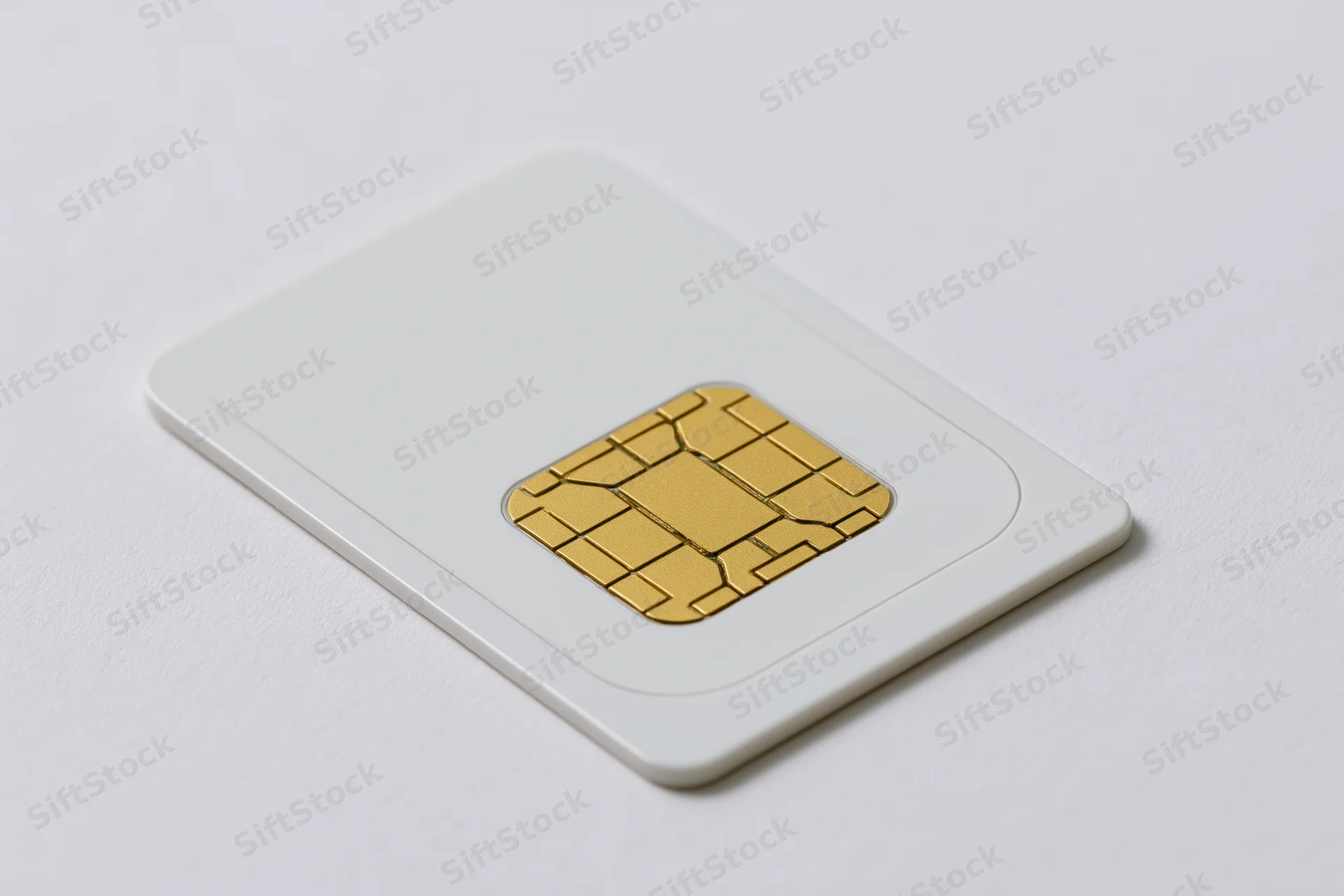 White sim card with gold contact chip photographed on plain surface