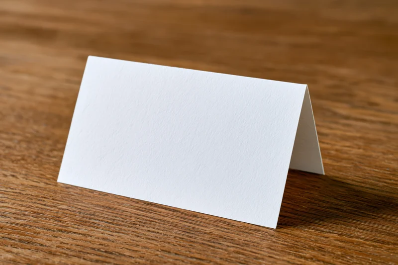 Blank white folded tent card standing upright on warm oak tabletop