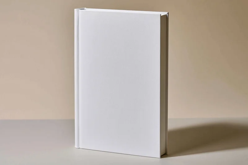 Blank white hardcover book standing upright on a smooth surface