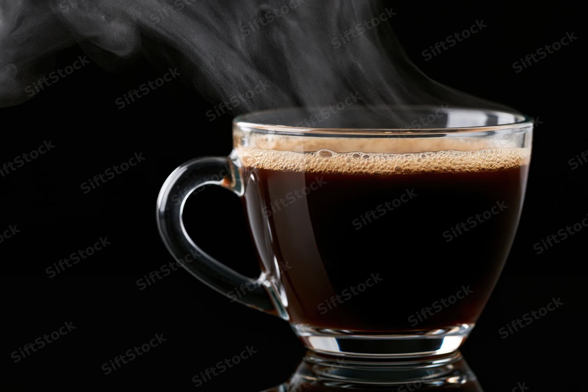 Hot black coffee steaming in a clear glass cup on a dark background