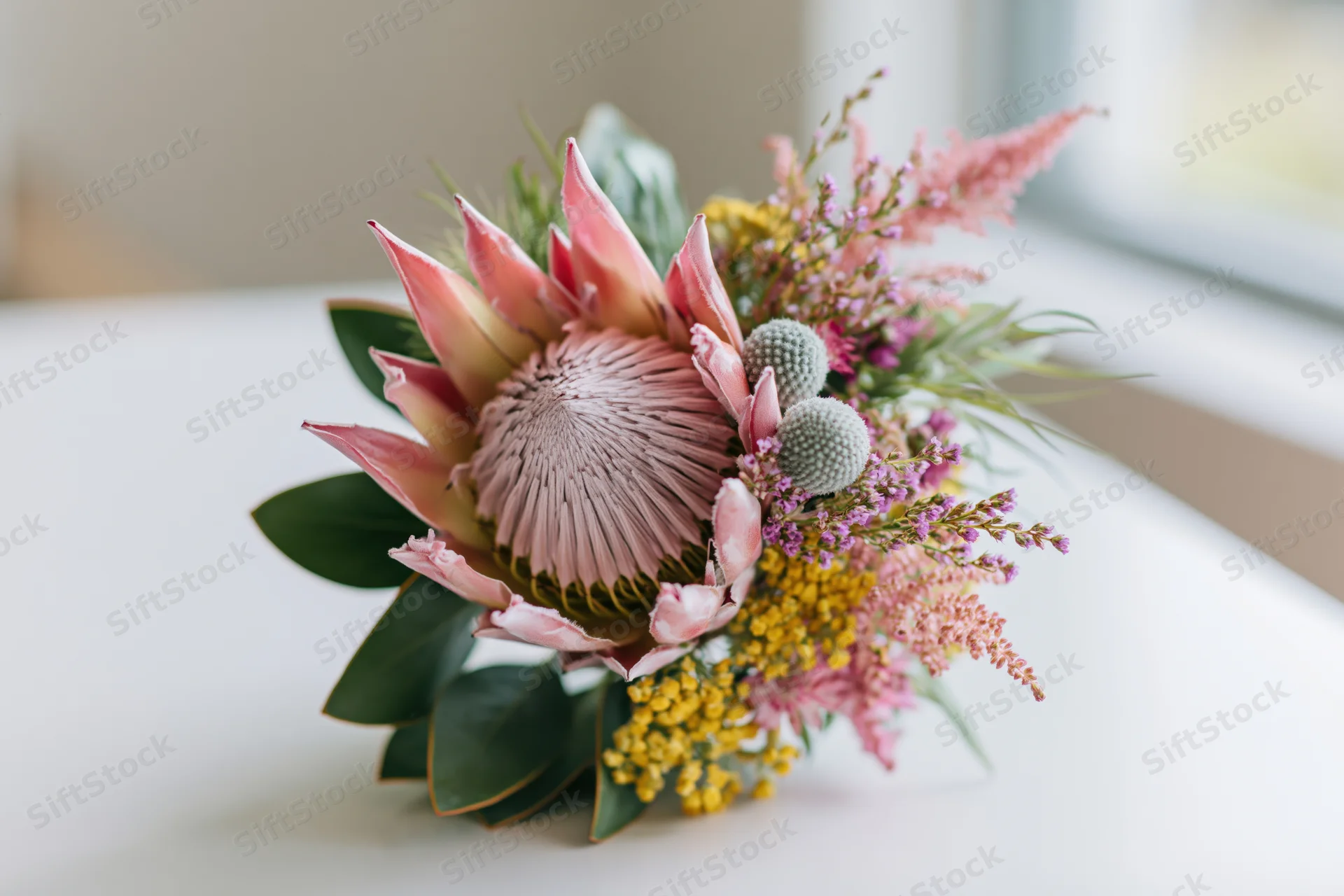 King protea at center of mixed wildflower bouquet on white surface
