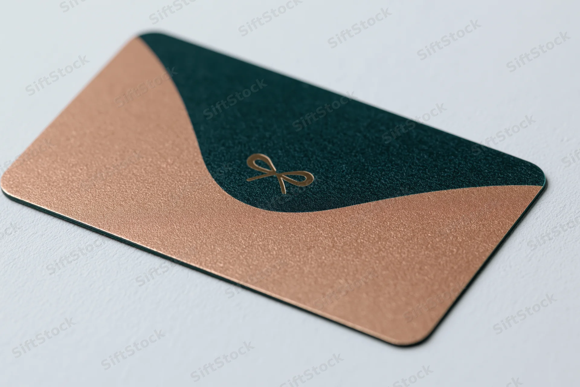 Luxury gift card with teal and rose gold design lying flat at an angle on white surface