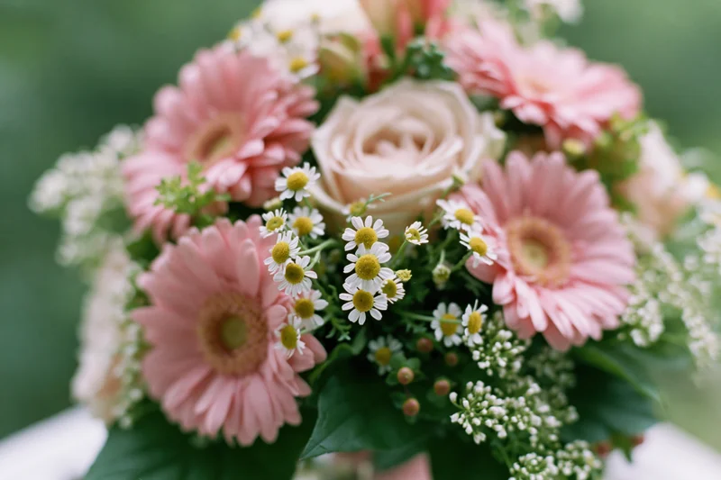 Mixed flower bouquet with pink gerberas, roses, and daisies resting on a surface
