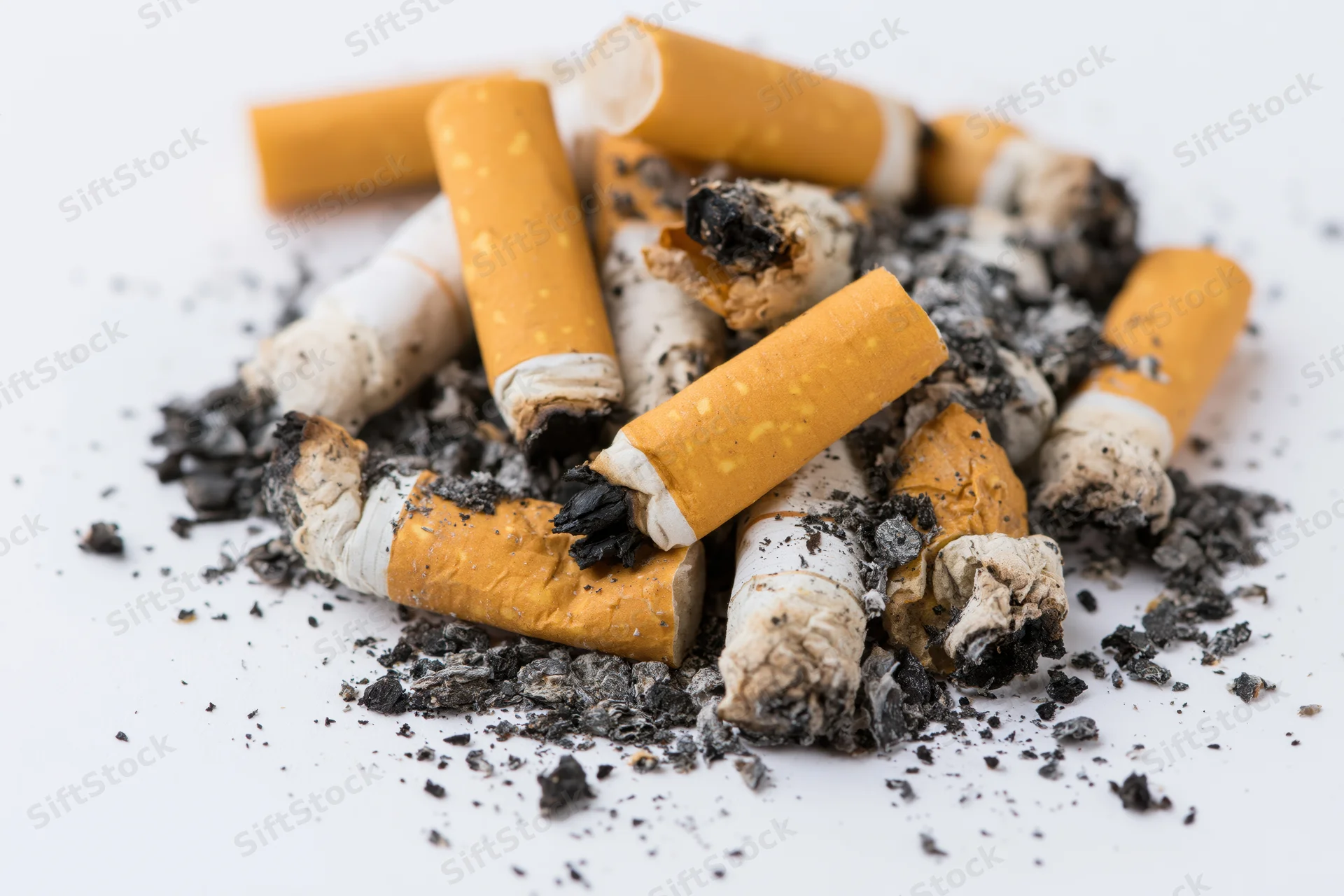 Pile of used cigarette butts with ash and char on white background