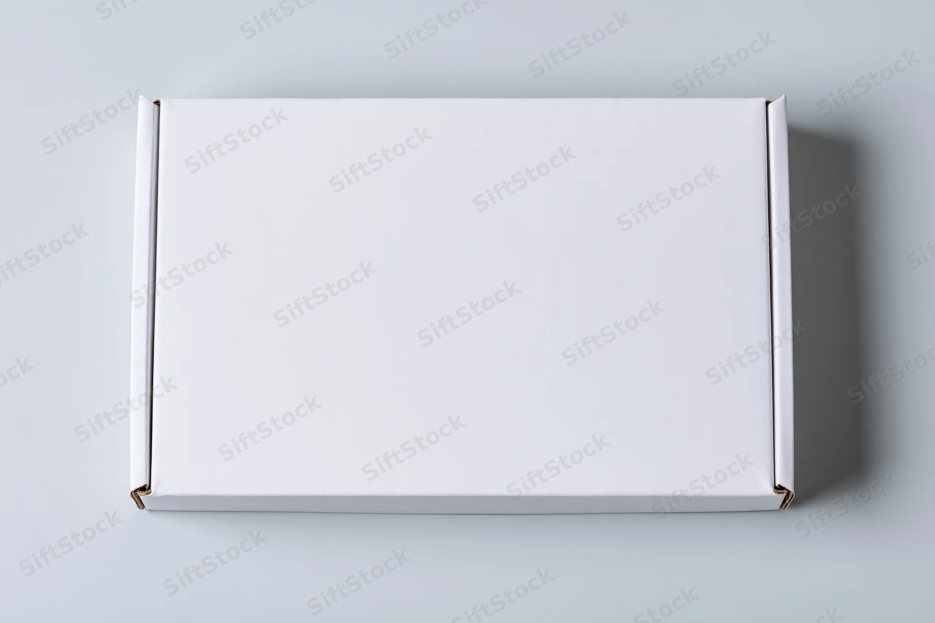 Plain white rectangular cardboard mailer box closed and centered on a light gray surface