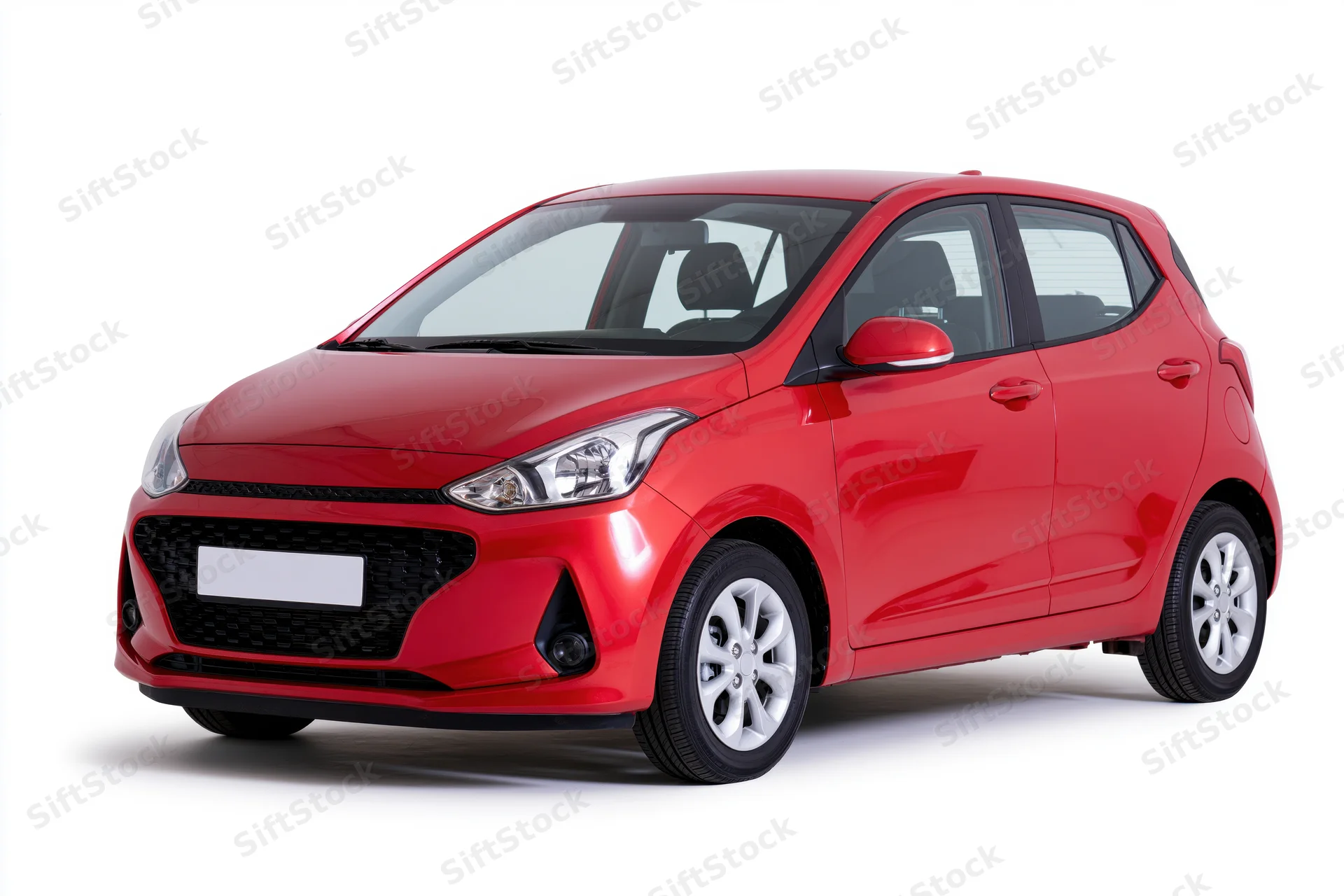 Red compact hatchback car parked in studio with white background