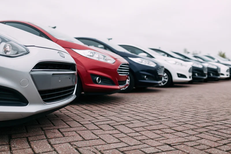 Row of compact cars parked diagonally on brick pavement