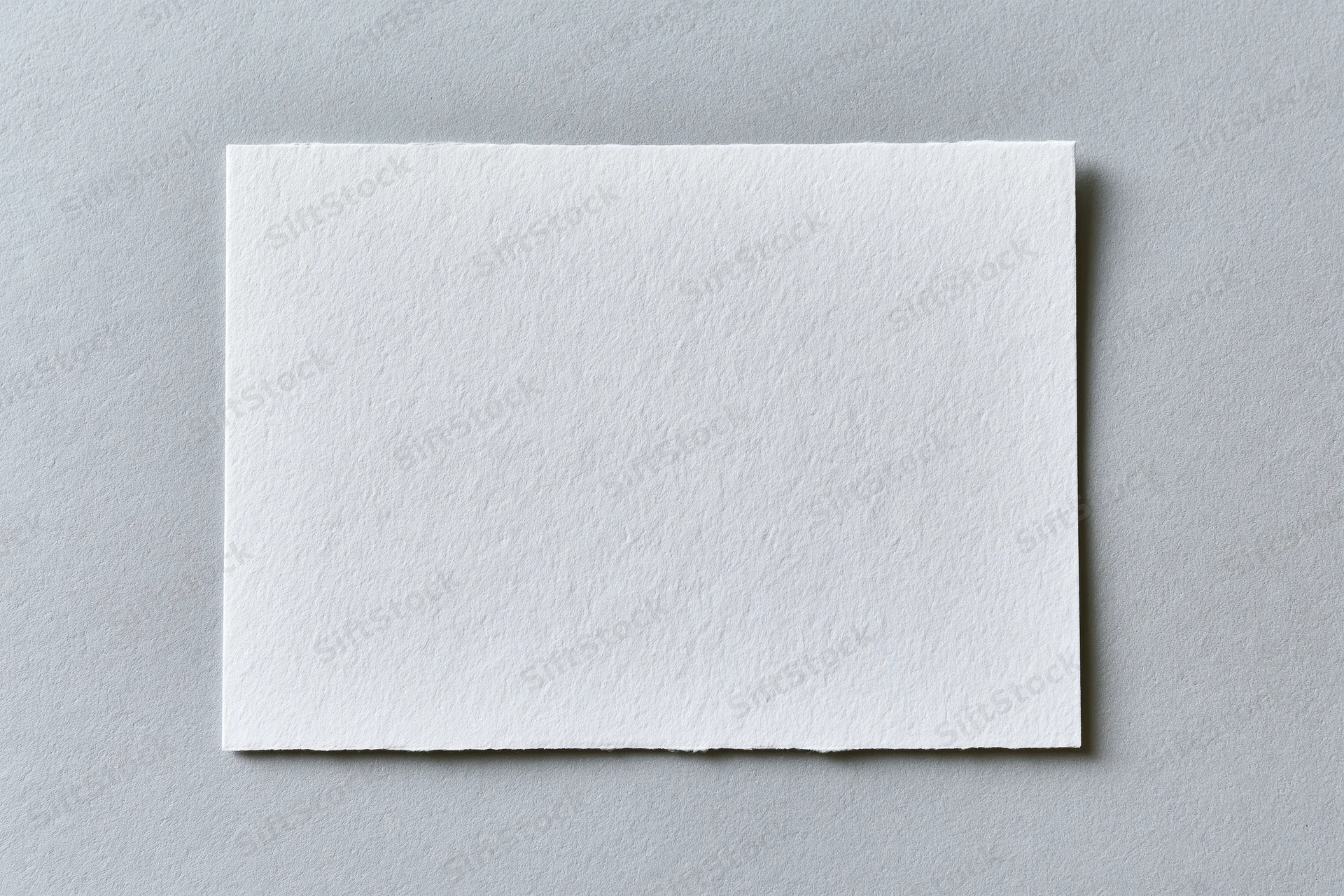 Blank white textured paper card centered on flat gray surface
