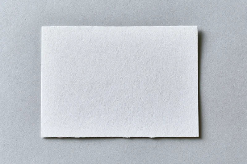 Blank white textured paper card centered on flat gray surface