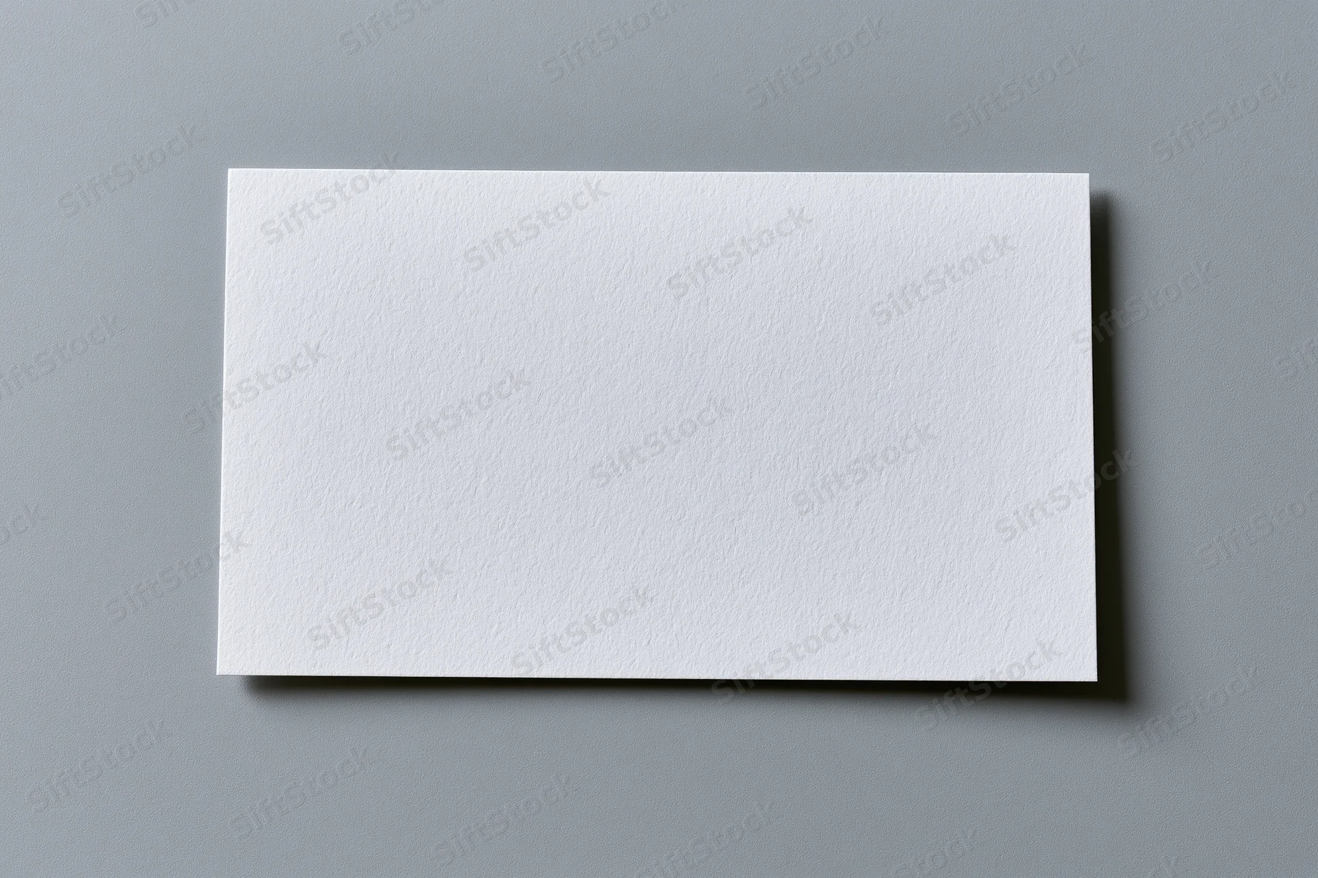 Blank white textured paper card centered on flat gray surface